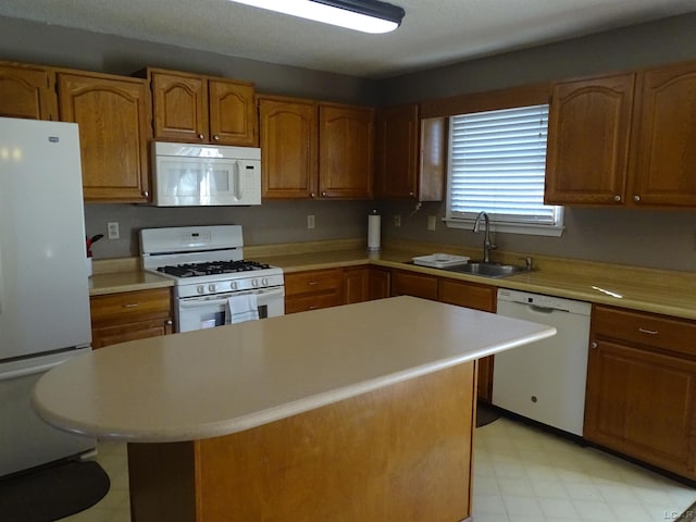 kitchen featuring a kitchen island, white appliances, and sink