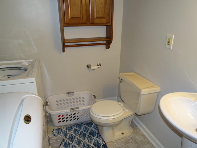 bathroom featuring washer / clothes dryer, toilet, and sink