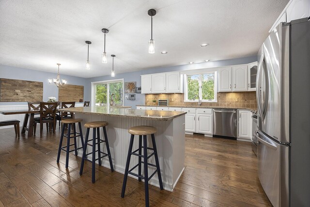 11600 Baker Rd, Greenville, MI 48838 - kitchen with stainless steel appliances, dark wood-type flooring, white cabinets, backsplash, and a kitchen island