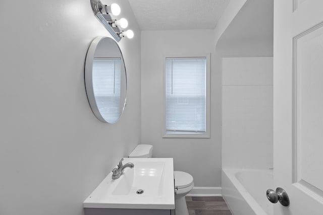 bathroom with vanity, toilet, wood-type flooring, and a textured ceiling