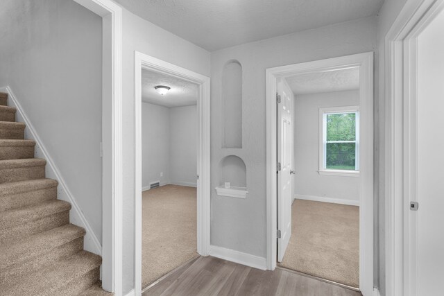 corridor with light hardwood / wood-style flooring and a textured ceiling