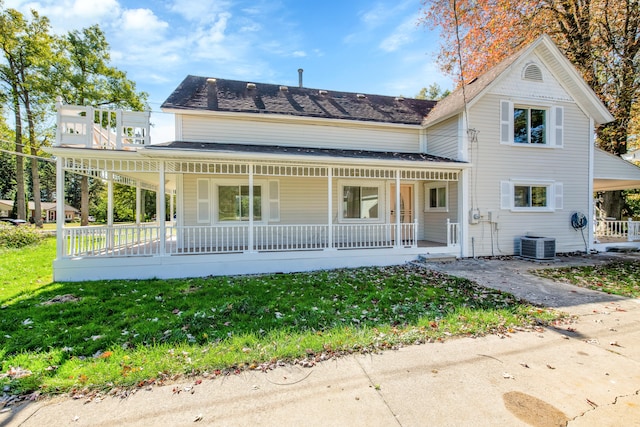 back of property featuring central AC unit, covered porch, and a yard