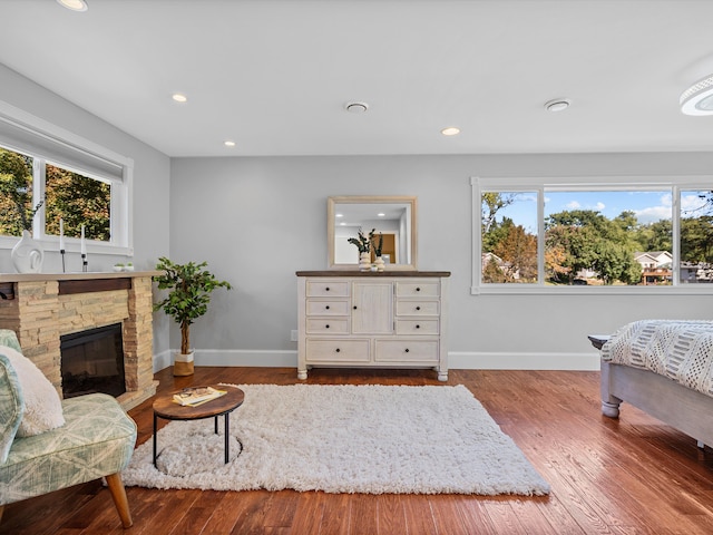 bedroom featuring multiple windows, a fireplace, and hardwood / wood-style flooring