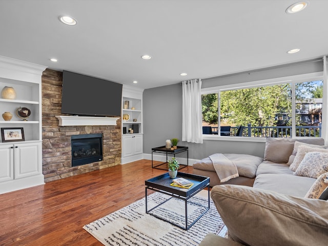 living room featuring a fireplace, wood-type flooring, and built in shelves