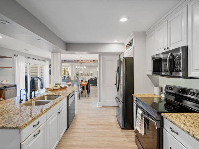 kitchen featuring appliances with stainless steel finishes, light stone counters, white cabinetry, and sink