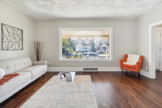 sitting room featuring a textured ceiling, ornamental molding, and dark wood-type flooring