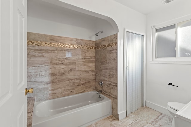 bathroom with toilet and tiled shower / bath