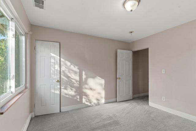 unfurnished bedroom with light colored carpet and a closet