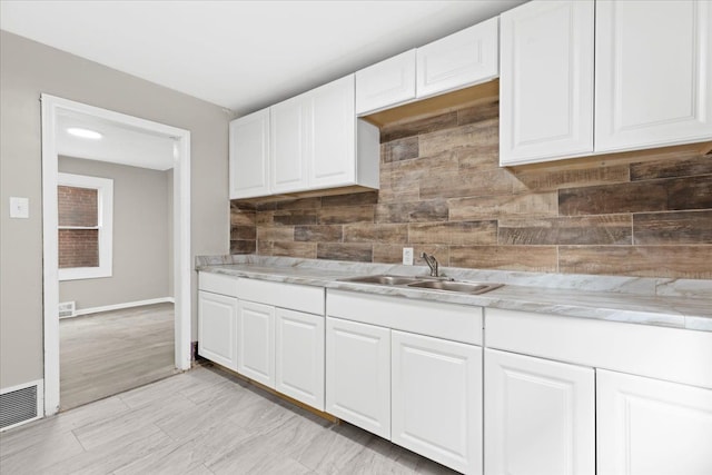 kitchen featuring white cabinets, backsplash, light hardwood / wood-style flooring, and sink