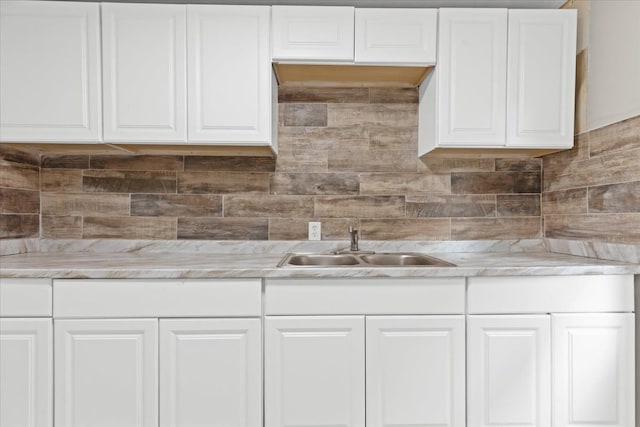 kitchen featuring white cabinets, backsplash, and sink