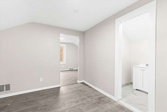 spare room with wood-type flooring and vaulted ceiling