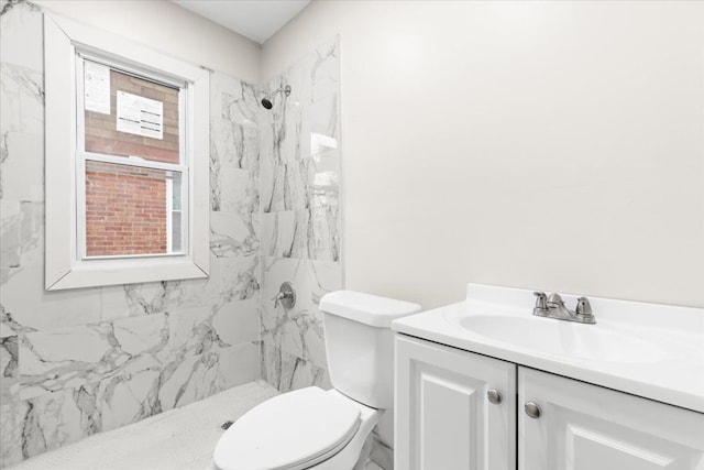 bathroom with vanity, toilet, and tiled shower