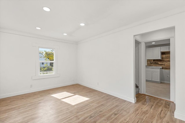 unfurnished room with crown molding and light wood-type flooring