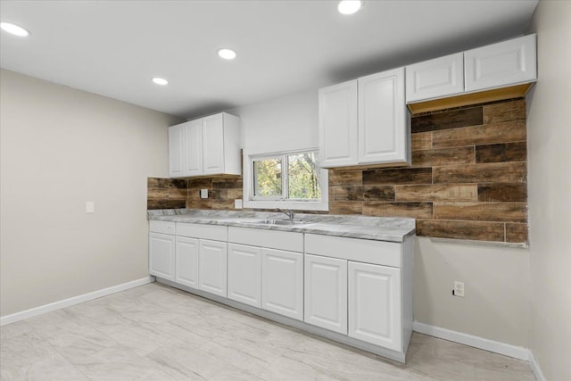 kitchen featuring white cabinets, backsplash, and sink