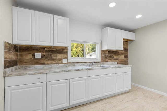 kitchen with white cabinets, decorative backsplash, and sink