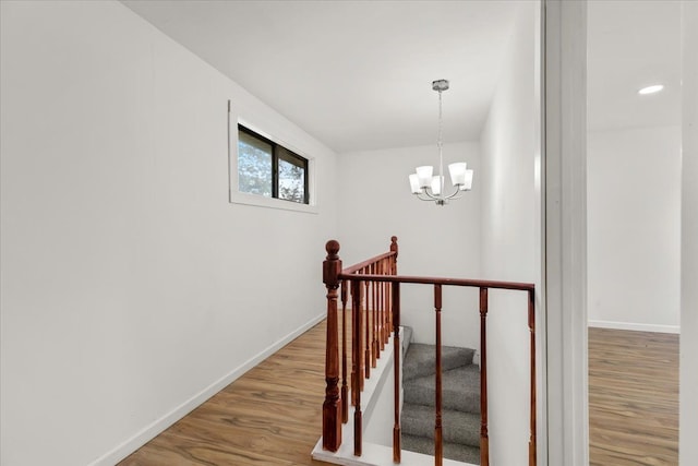 stairs featuring hardwood / wood-style flooring and an inviting chandelier