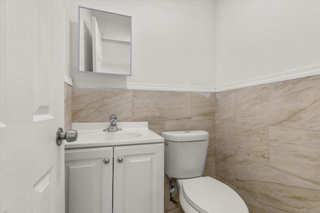 bathroom with vanity, toilet, and tile walls