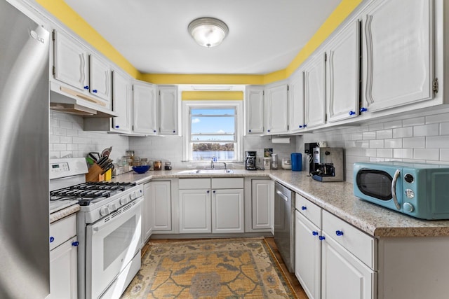 kitchen featuring sink, light stone countertops, appliances with stainless steel finishes, tasteful backsplash, and white cabinetry