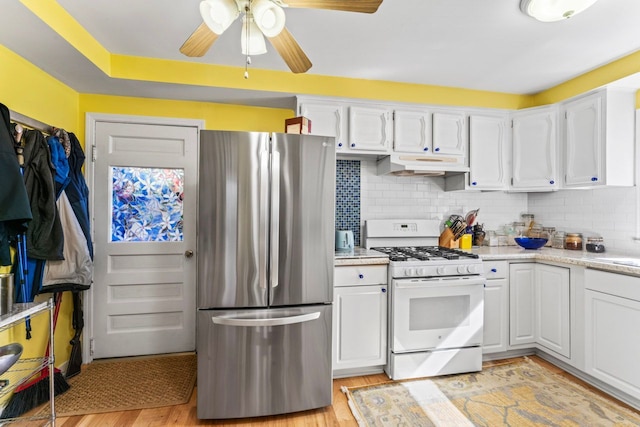 kitchen featuring stainless steel refrigerator, white cabinetry, tasteful backsplash, white range with gas stovetop, and light hardwood / wood-style floors