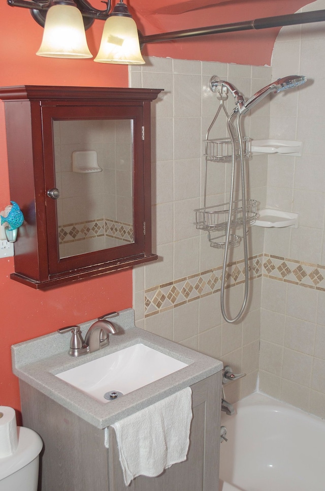 full bathroom featuring vanity, tiled shower / bath combo, and toilet