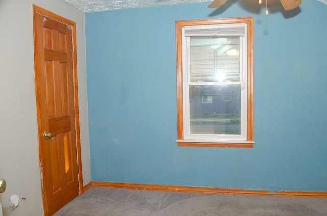 carpeted spare room featuring a textured ceiling and ceiling fan