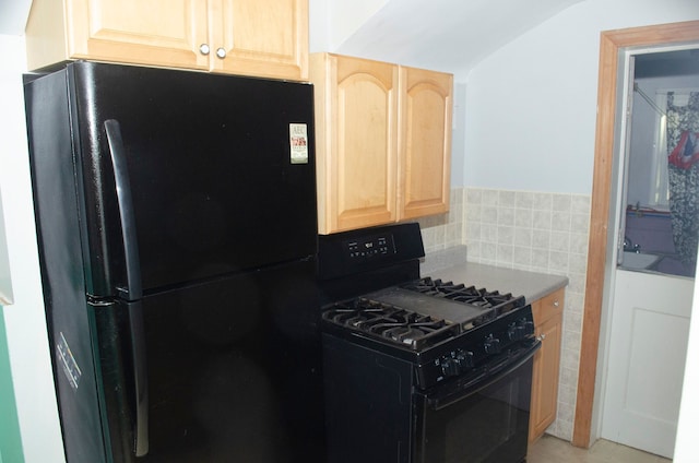 kitchen with black appliances, light brown cabinets, tasteful backsplash, and vaulted ceiling