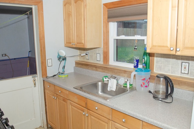 kitchen with backsplash, light brown cabinetry, and sink