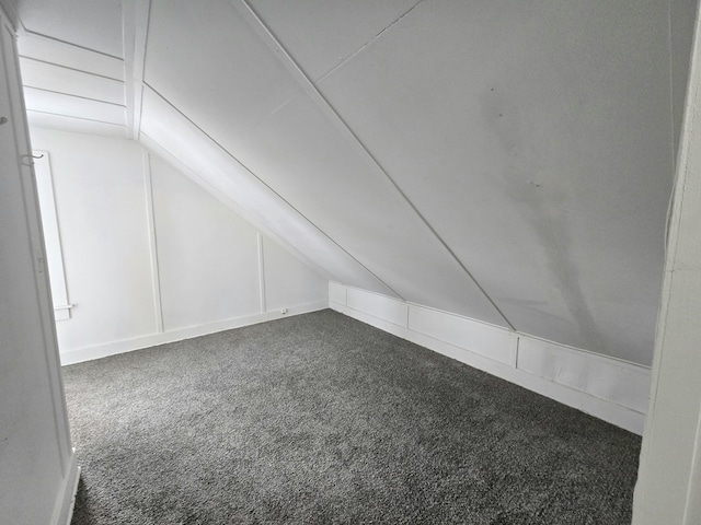 bonus room with vaulted ceiling and dark colored carpet