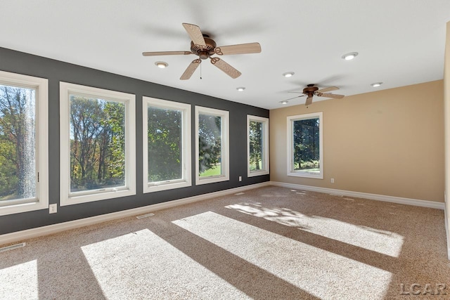 empty room with carpet flooring, ceiling fan, and a healthy amount of sunlight