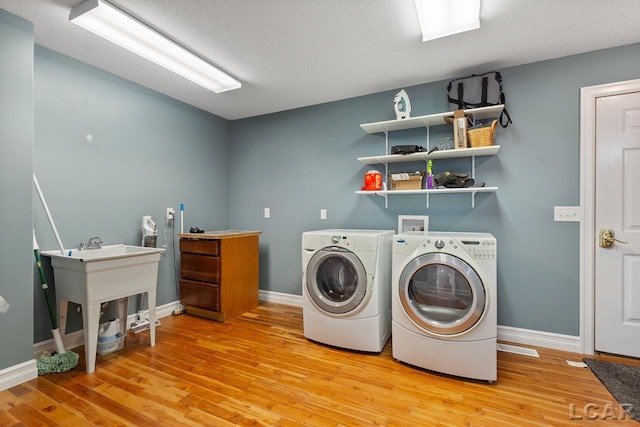 clothes washing area featuring wood-type flooring, a textured ceiling, and washing machine and clothes dryer