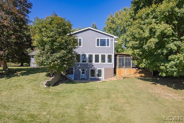 rear view of property featuring a sunroom, a yard, and a wooden deck