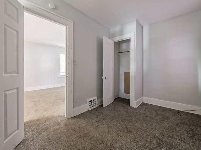 unfurnished bedroom featuring dark colored carpet and a closet