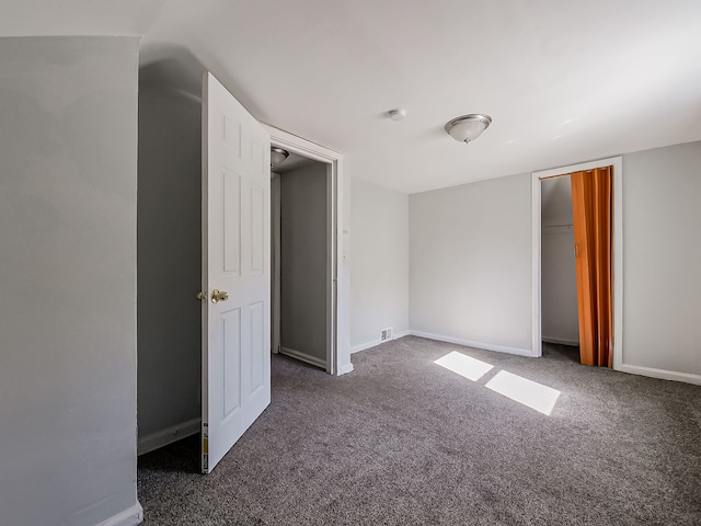 unfurnished bedroom with dark carpet and a closet