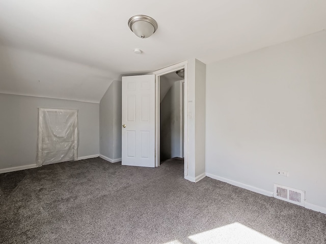 additional living space with dark colored carpet and vaulted ceiling