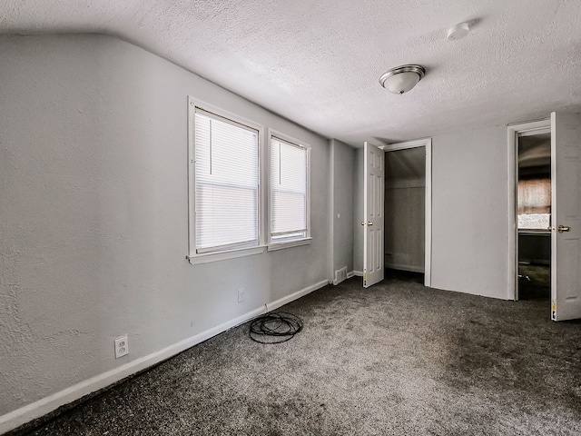 unfurnished bedroom with carpet floors, a textured ceiling, and vaulted ceiling