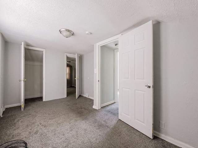 unfurnished bedroom featuring a textured ceiling and dark colored carpet