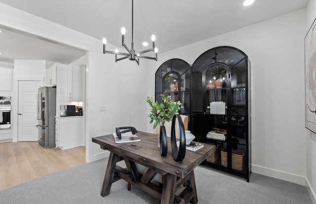 dining area with light carpet and a notable chandelier