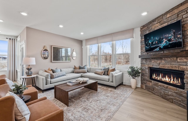 living room featuring light wood-type flooring and a stone fireplace