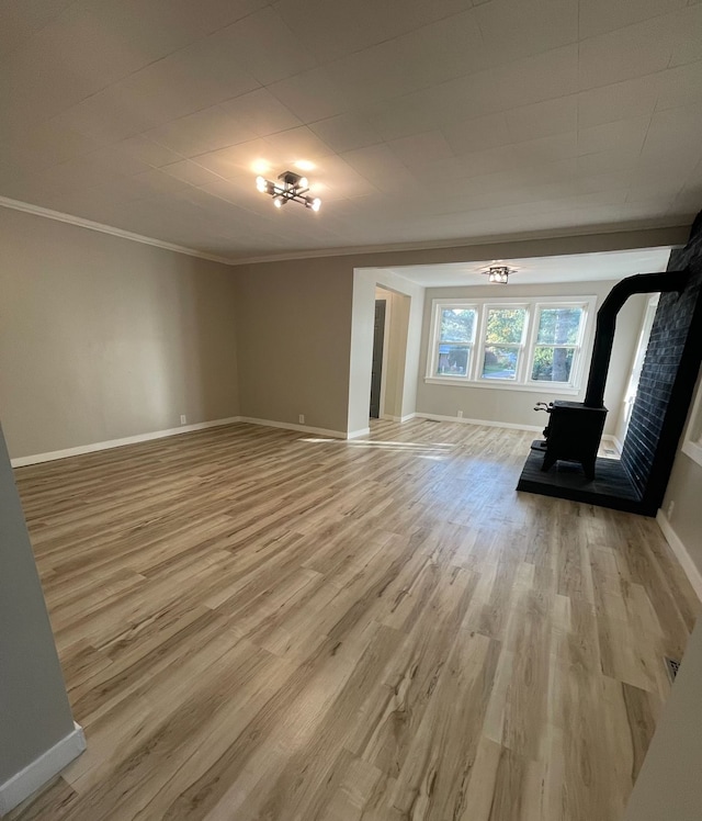 unfurnished living room with crown molding, a wood stove, and light hardwood / wood-style flooring