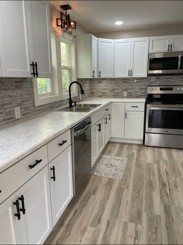 kitchen featuring sink, appliances with stainless steel finishes, tasteful backsplash, light stone countertops, and white cabinets