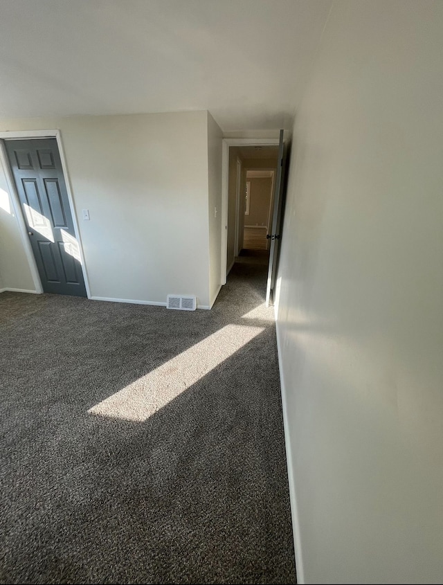 spare room featuring dark carpet