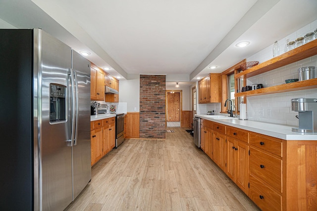 kitchen featuring tasteful backsplash, sink, stainless steel appliances, and light wood-type flooring