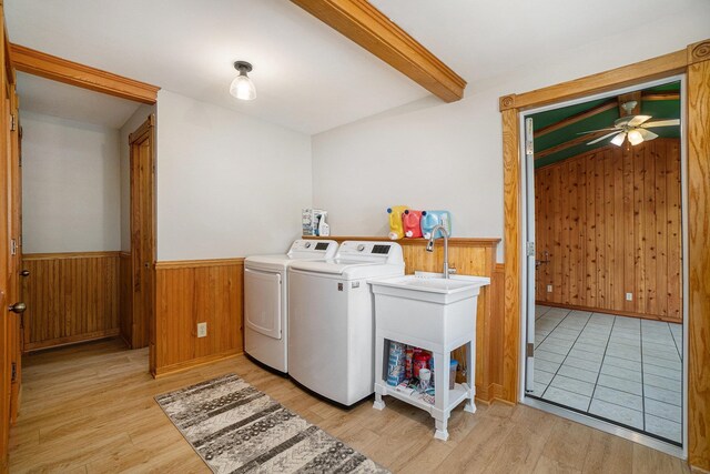 clothes washing area with wooden walls, washer and clothes dryer, ceiling fan, and light hardwood / wood-style floors