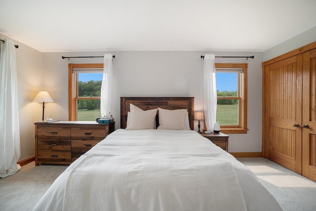 bedroom with light carpet, a closet, and multiple windows