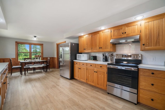 kitchen with decorative backsplash, light wood-type flooring, and stainless steel appliances