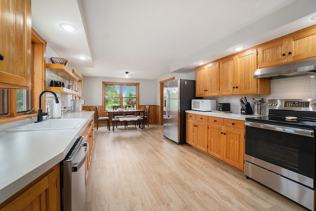 kitchen featuring tasteful backsplash, sink, appliances with stainless steel finishes, and light hardwood / wood-style flooring