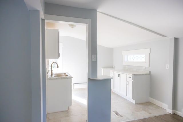 kitchen featuring sink, white cabinets, and light wood-type flooring