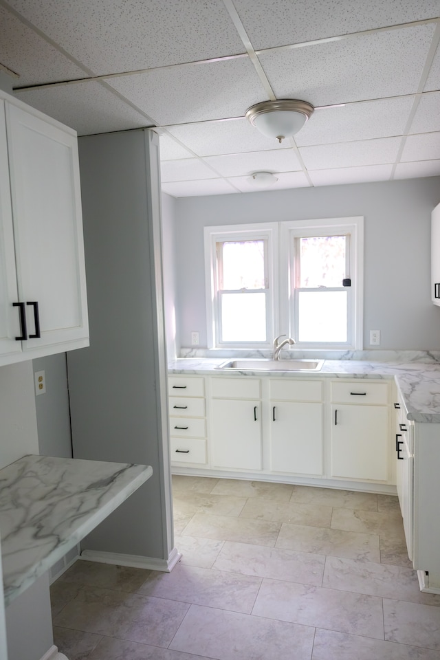 kitchen featuring a drop ceiling, white cabinetry, and sink