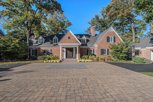 view of front of home with brick siding and a chimney