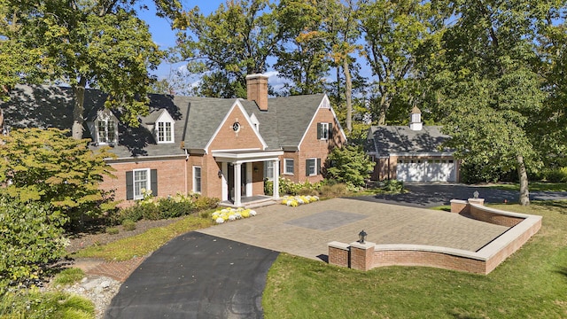 view of front of property with a front lawn, brick siding, an outdoor structure, and a chimney